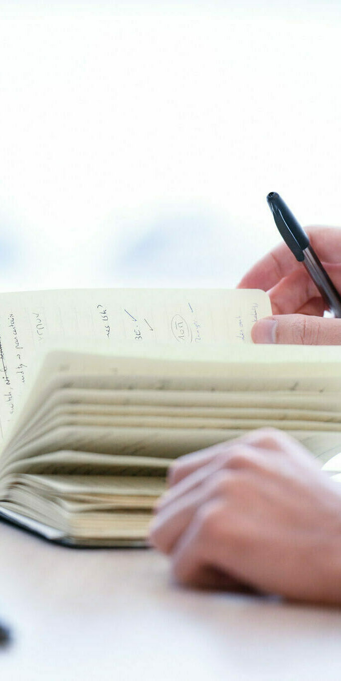 Photographie d’une main qui tient une page d’un carnet ouvert Photographie d'une main qui tient une page d'un carnet ouvert