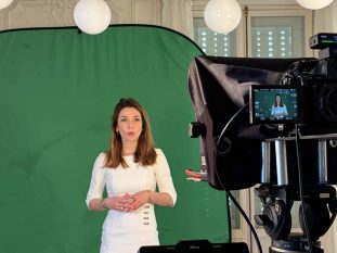Responsable d'entreprise en tournage d'interview vidéo sur fond vert, filmée par une équipe professionnelle.