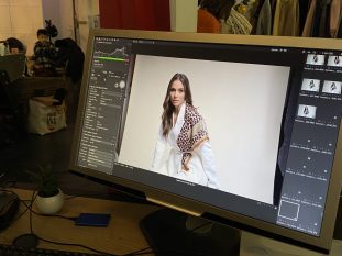 Vue d'un poste de travail professionnel avec un moniteur Philips affichant un plan de montage vidéo d'un mannequin. Un clavier KeyQuest, une souris et des éléments de studio sont visibles en premier plan et en arrière-plan.